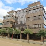 Modern office building with glass windows and trees.