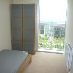 Modern bedroom with large window view of buildings