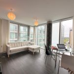 Modern apartment with large windows and white furniture.