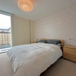 Modern bedroom with large window and stylish decor.