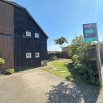 Wooden house with 'Let' sign in driveway.