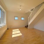 Bright room with stairs and wooden floor.