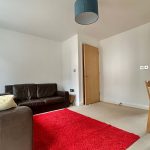 Modern living room with red rug and leather sofa.