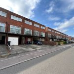 Row of terraced houses with garages and driveways.