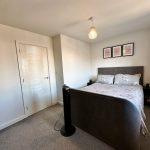 Modern bedroom with grey bed and floral bedding.