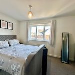 Modern bedroom with large bed and window view.