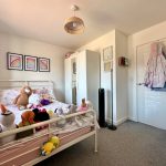 Child's bedroom with stuffed toys and rainbow decor.