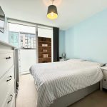 Modern bedroom with striped bedding and city view.