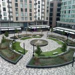 Modern urban courtyard with circular fountain and benches.