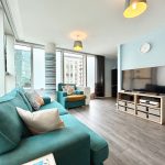 Modern living room with teal furniture and TV.