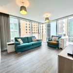 Modern living room with teal sofas and city view.