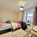 Cosy bedroom with suitcase and window view.
