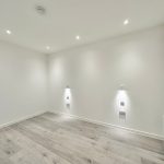 Minimalist empty room with wooden flooring and lights.