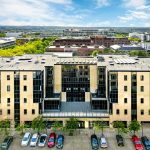 Modern office building with parked cars, sunny day.