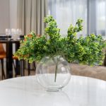 Glass vase with green plant on table