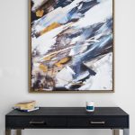 Abstract painting above modern black console table.