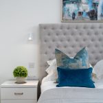 Modern bedroom with grey headboard and blue pillows