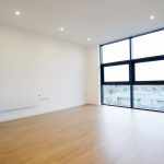 Spacious room with wooden floors and large windows.