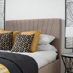 Modern bedroom with pattern cushions and art decor.