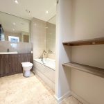 Modern bathroom with tiles and wooden cabinets.