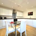 Modern kitchen with white cabinets and dining table.