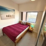 Cosy bedroom with double bed and large window view.