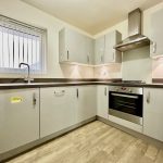 Modern kitchen with oven and grey cabinets.