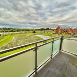 Balcony view of fields and modern buildings.