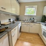 Modern kitchen with appliances and wooden flooring.