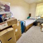 Small bedroom packed with boxes and single bed.