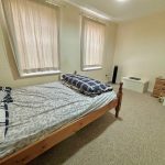 Simple bedroom with bed, drawers, and curtains.