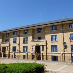 Modern three-storey brick apartment building with blue windows.