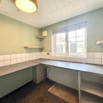 Empty kitchen with shelves and large window.