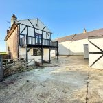Rustic house with wooden balcony and open courtyard.