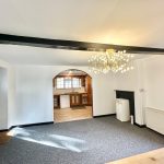 Spacious room with chandelier and open kitchen view.