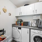 Modern utility room with washer, dryer, and storage space.