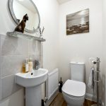 Modern white bathroom with mirror and decor.