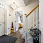 Bright entrance hallway with stairs and doorway view.