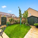 Sunny garden with shed and patio furniture.