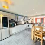 Modern kitchen with dining table and stainless steel appliances.