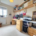 Home office with desk, shelves, and window.