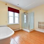 Spacious bathroom with freestanding tub and glass shower.