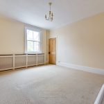 Spacious room with window, beige walls, and carpet.