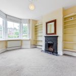 Empty living room with fireplace and bay window.