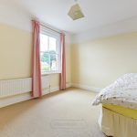 Bright bedroom with single bed and pink curtains.