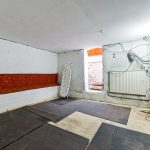 Minimalist basement with mats and exposed wiring.