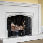 White ornamental fireplace with black interior.