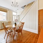 Spacious dining room with wooden furniture and stairs.
