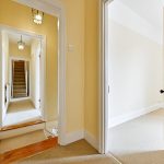 Bright hallway with stairs and open door.