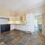 Spacious kitchen with white cabinets and slate floor.